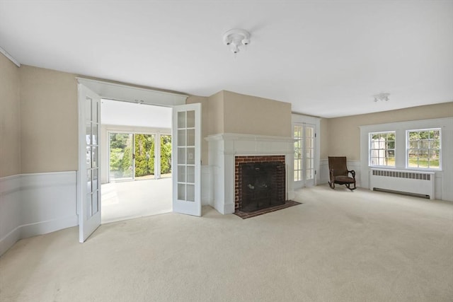 36 Uncle Barneys Rd, Dennis, MA 02670 - unfurnished living room with radiator, carpet, a brick fireplace, and french doors