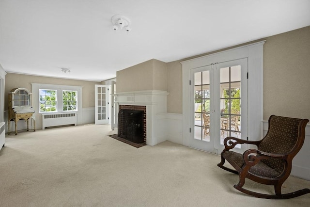 36 Uncle Barneys Rd, Dennis, MA 02670 - living room with radiator heating unit, french doors, carpet flooring, a wainscoted wall, and a brick fireplace