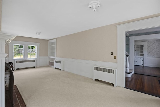 36 Uncle Barneys Rd, Dennis, MA 02670 - unfurnished living room featuring radiator, carpet, wainscoting, and a decorative wall