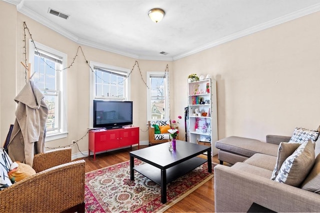 living area featuring crown molding, wood finished floors, baseboards, and visible vents