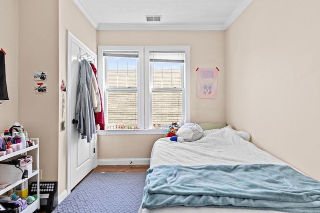 bedroom with visible vents, baseboards, ornamental molding, and wood finished floors