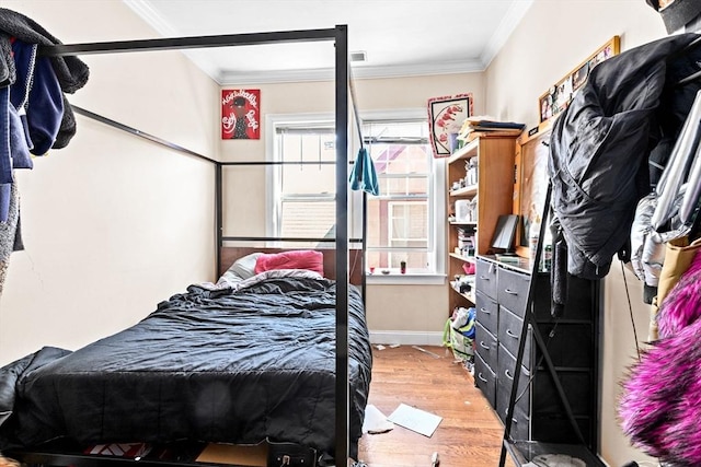 bedroom featuring visible vents, baseboards, ornamental molding, and wood finished floors