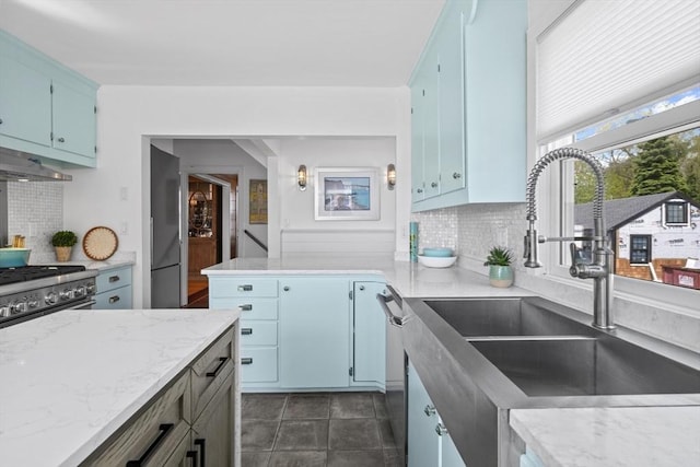 13 Selman St, Marblehead, MA 01945 - kitchen with a sink, decorative backsplash, blue cabinets, appliances with stainless steel finishes, and under cabinet range hood