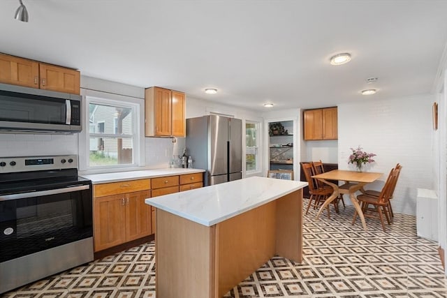 12 Temple Ave, Hudson, MA 01749 - kitchen with stainless steel appliances, light flooring, decorative backsplash, a center island, and brown cabinets