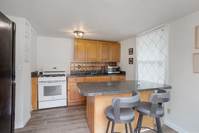 12 Temple Ave, Hudson, MA 01749 - kitchen featuring white range with gas cooktop, stainless steel microwave, freestanding refrigerator, a kitchen bar, and dark countertops