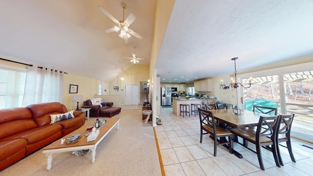 tiled dining area with high vaulted ceiling and ceiling fan with notable chandelier