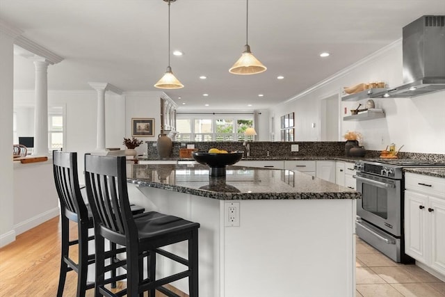 1 Bridge Ln, Newburyport, MA 01950 - kitchen featuring wall chimney range hood, stainless steel gas stove, ornate columns, open shelves, and white cabinetry