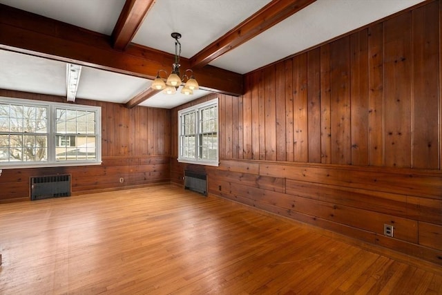 spare room with wooden walls, a notable chandelier, light wood-style flooring, and radiator heating unit