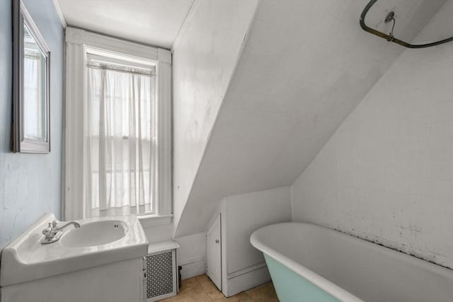 bathroom featuring lofted ceiling, radiator heating unit, a soaking tub, and vanity