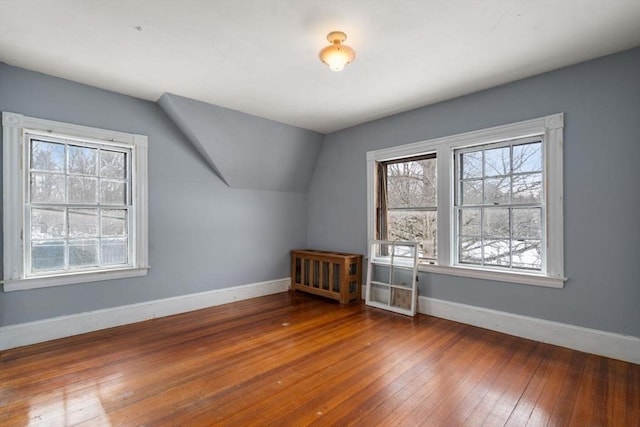 bonus room with wood-type flooring, vaulted ceiling, and baseboards