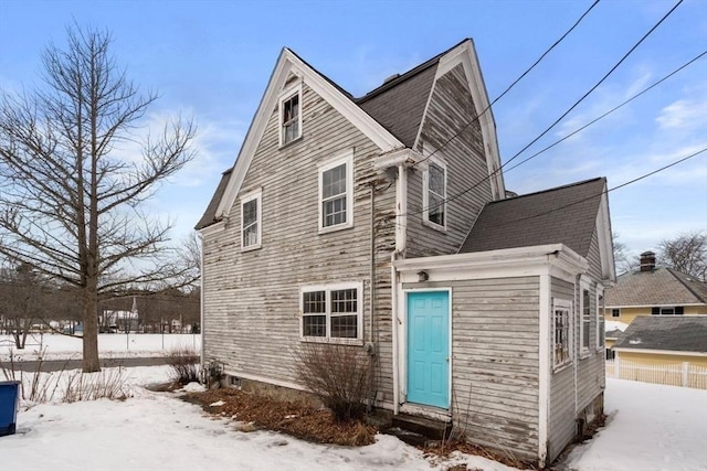 snow covered property with entry steps and a gambrel roof