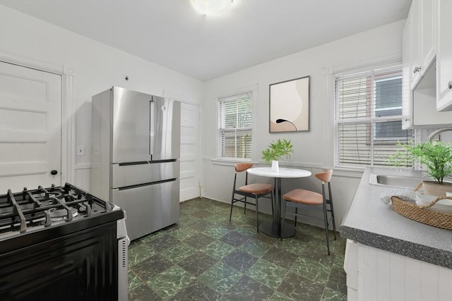 69 Dracut, Boston, MA 02124 - kitchen featuring freestanding refrigerator, gas stove, dark floors, and white cabinetry