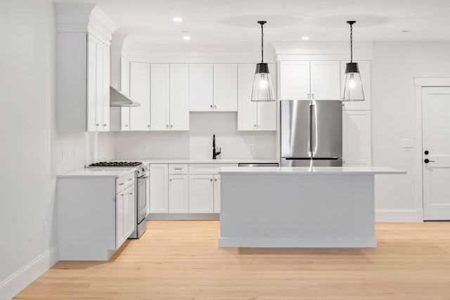 kitchen with sink, appliances with stainless steel finishes, pendant lighting, white cabinets, and light wood-type flooring