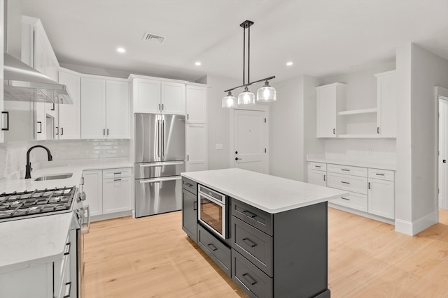 kitchen with gray cabinetry, white cabinetry, light hardwood / wood-style flooring, a kitchen island, and appliances with stainless steel finishes