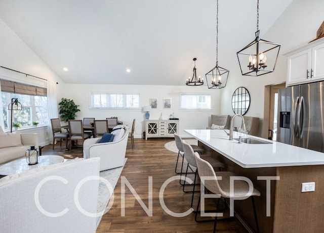 kitchen featuring sink, dark wood-type flooring, decorative light fixtures, a center island with sink, and white cabinets