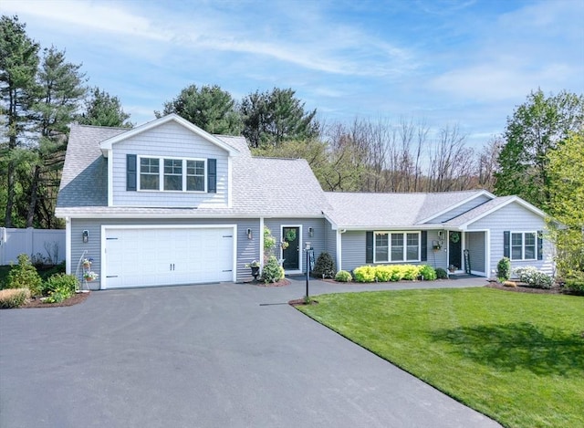 traditional-style house featuring a garage, fence, aphalt driveway, a shingled roof, and a front yard