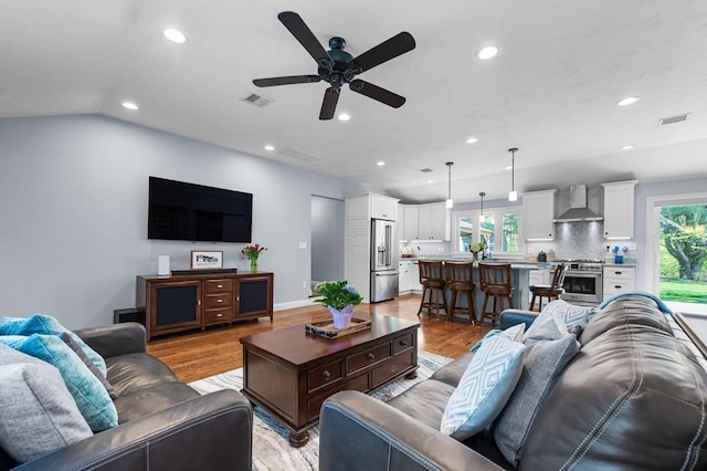 living area with light wood-style flooring, a ceiling fan, visible vents, and recessed lighting