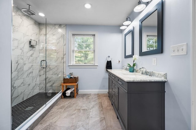full bath with a sink, marble finish floor, a stall shower, double vanity, and baseboards