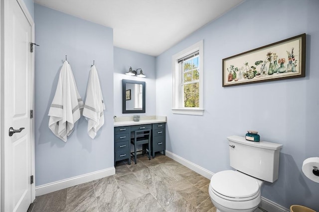 bathroom featuring baseboards, toilet, and vanity