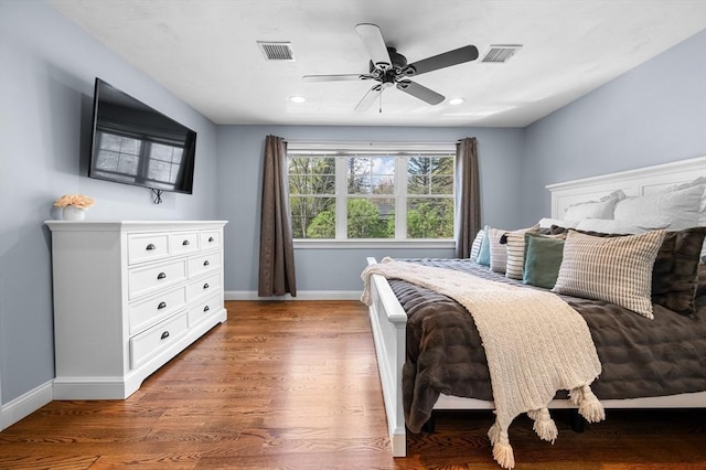 bedroom featuring baseboards, ceiling fan, visible vents, and wood finished floors