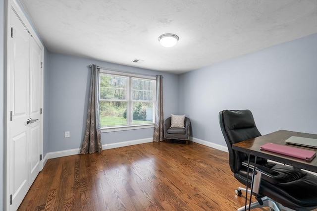 office area featuring baseboards, visible vents, and wood finished floors