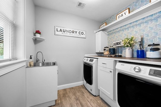 laundry area with a sink, washing machine and clothes dryer, cabinet space, and visible vents
