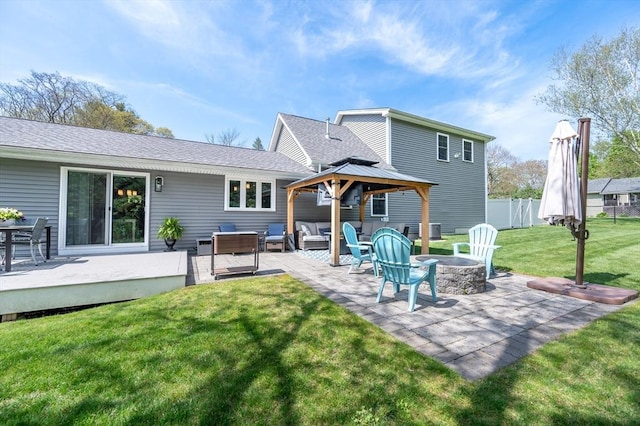 back of property with a lawn, fence, a wooden deck, a gazebo, and an outdoor living space with a fire pit