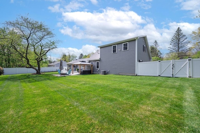 back of house with a lawn, central AC, a gazebo, a fenced backyard, and a gate