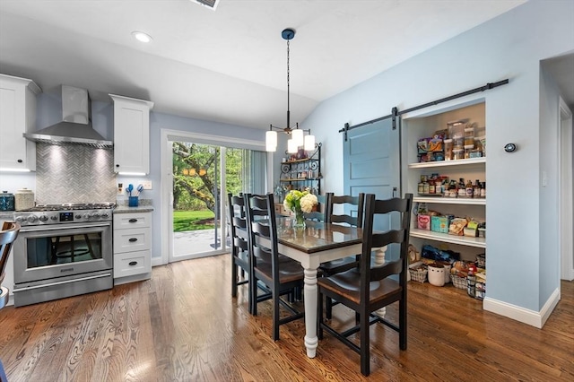 dining room featuring wood finished floors, a barn door, recessed lighting, vaulted ceiling, and baseboards