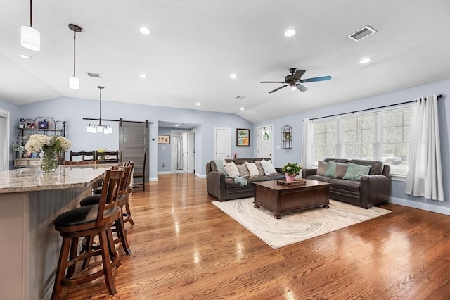 living area featuring visible vents, a barn door, lofted ceiling, and ceiling fan