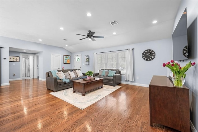 living room with light wood-style flooring, baseboards, ceiling fan, visible vents, and vaulted ceiling