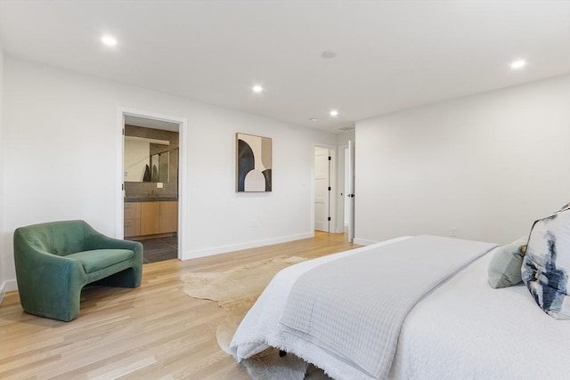 bedroom with connected bathroom and hardwood / wood-style floors