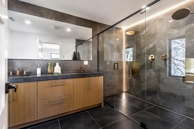 bathroom featuring tile walls, tile patterned flooring, vanity, decorative backsplash, and walk in shower