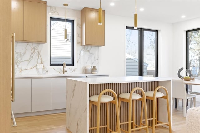 kitchen featuring pendant lighting, light brown cabinetry, a breakfast bar area, and sink