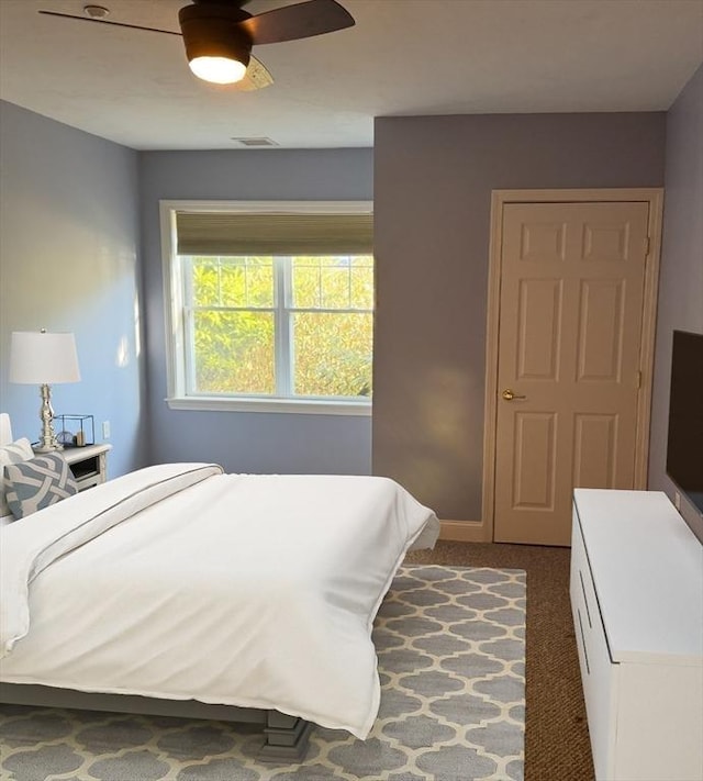 bedroom with dark colored carpet, visible vents, and ceiling fan