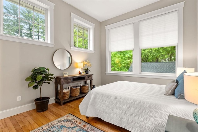 bedroom with multiple windows, hardwood / wood-style flooring, and baseboards
