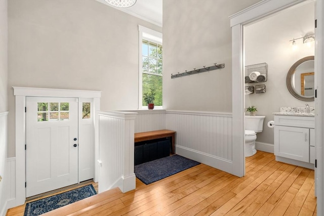 foyer entrance with wainscoting, light wood finished floors, and healthy amount of natural light