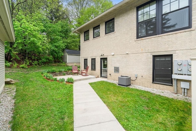 back of house featuring a patio area, a yard, central AC, and brick siding