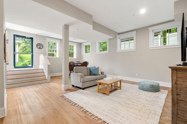 living room featuring baseboards, wood finished floors, and stairway