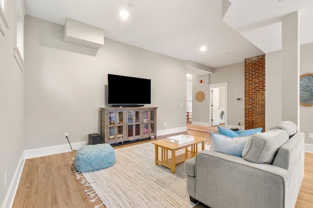 living room with wood finished floors, baseboards, washer / clothes dryer, a fireplace, and recessed lighting