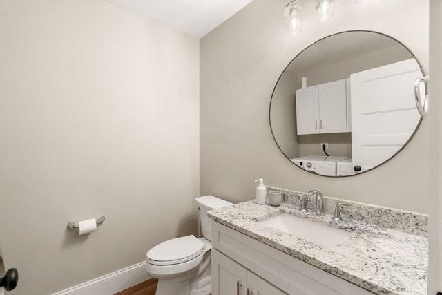 half bathroom with toilet, vanity, baseboards, and wood finished floors