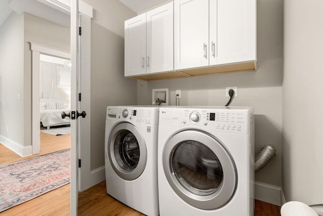 laundry room featuring wood finished floors, cabinet space, washer and clothes dryer, and baseboards
