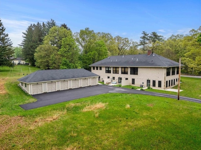 rear view of house featuring a lawn and an outbuilding