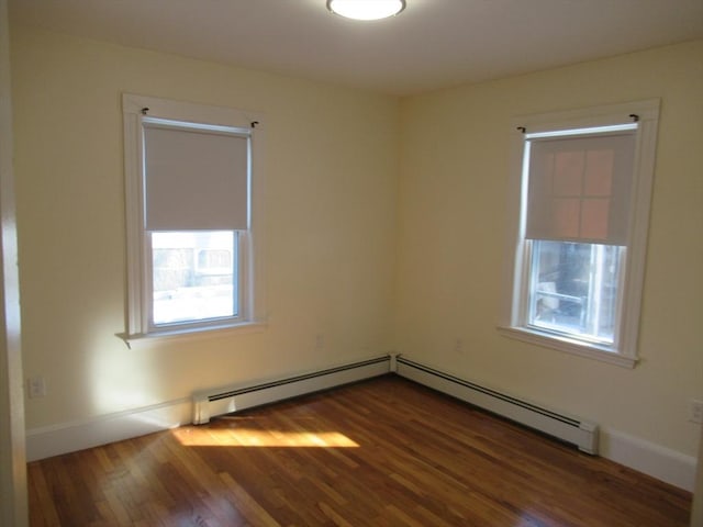 empty room with baseboard heating, a healthy amount of sunlight, and dark hardwood / wood-style flooring