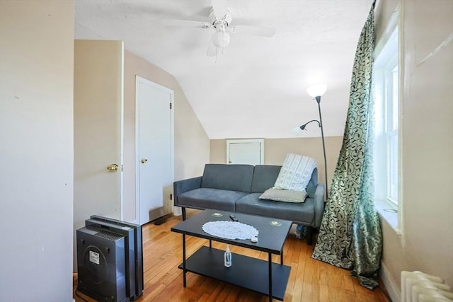 living room featuring ceiling fan, wood-type flooring, radiator heating unit, and vaulted ceiling