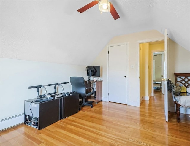 home office with vaulted ceiling, light hardwood / wood-style flooring, ceiling fan, baseboard heating, and a textured ceiling