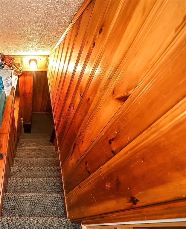 stairs featuring wood walls and a textured ceiling