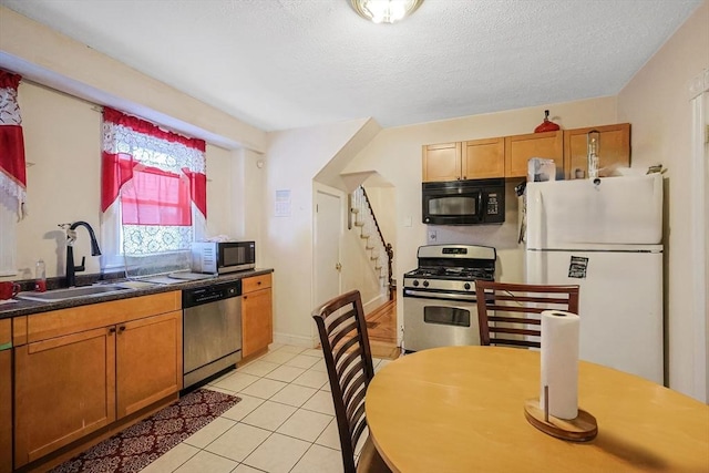 kitchen featuring a textured ceiling, light tile patterned floors, sink, and appliances with stainless steel finishes