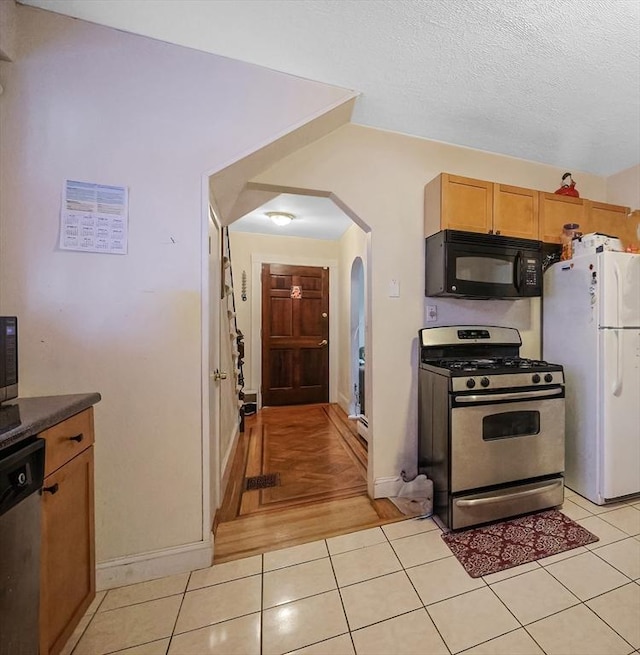 kitchen with appliances with stainless steel finishes, a textured ceiling, and light tile patterned floors