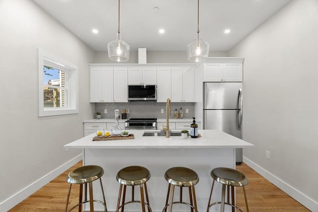 21 Ellington St Unit 2, Boston, MA 02121 - kitchen with stainless steel appliances, a breakfast bar area, decorative backsplash, a center island with sink, and white cabinets